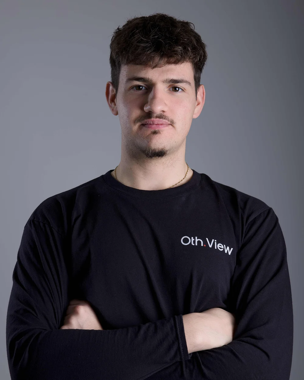 Janick Brändli mit dunklen Locken und verschränkten Armen im schwarzen Oth.View-Shirt