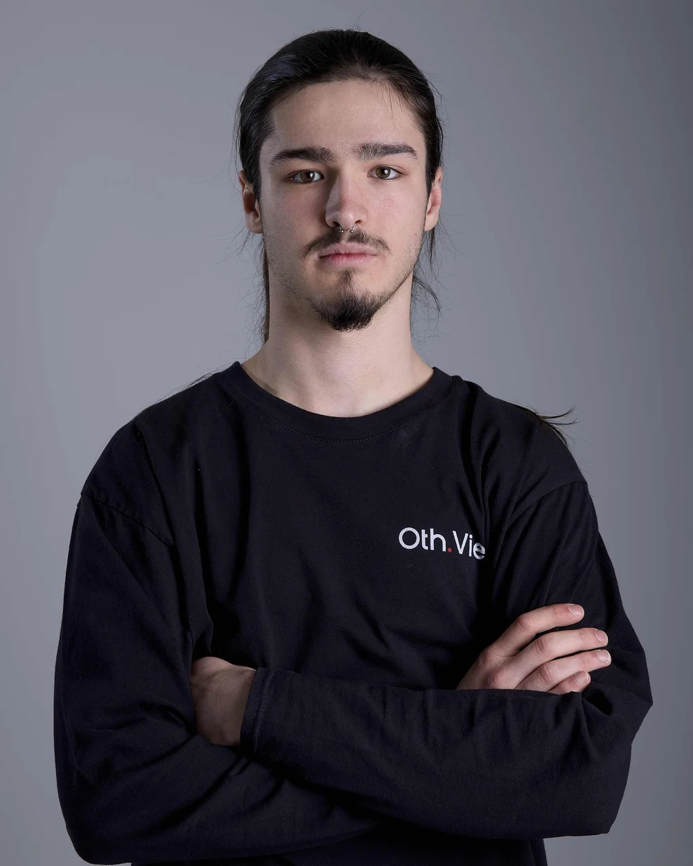 Severin Leuzinger mit zurückgebundenen Haaren und Bart, Arme verschränkt, im schwarzen Oth.View-Shirt