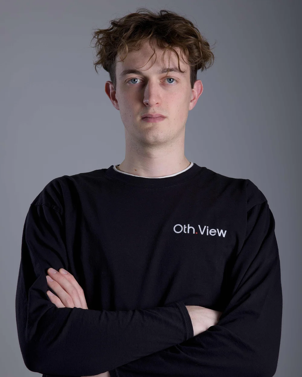 Timo Haas mit lockigem Haar und verschränkten Armen im schwarzen Oth.View-Shirt